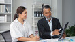 © amnaj - Experienced manager presenting marketing data on digital tablet to young colleague in modern office setting