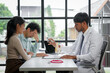 © amnaj - Doctor pointing at anatomical model of human spine and explaining diagnosis to worried couple during medical consultation