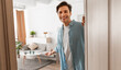 © Prostock-studio - Portrait of cheerful man welcoming inviting visitor to enter his home, happy young guy standing in doorway of modern apartment, millennial male holding door looking out showing living room with hand
