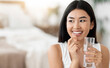 © Prostock-studio - Diet, nutrition, healthy eating concept. Close Up Of Happy Smiling Asian Woman Taking Supplement Pill And Holding Glass Of Fresh Water In Morning, copy space
