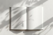 © vejaa - Open empty book with leaves shadow overlay on grunge white background. Top view to blank paper book, brochure, planner, diary