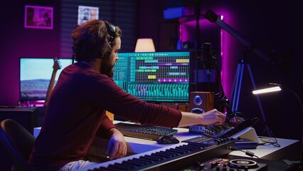 Aufkleber - Music producer engages in post production with editing and time aligning recorded songs. Musician using digital audio workstations to manipulate tunes, adding audio effects. Camera B.