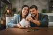 © Miljan Živković - Adult couple save money coins in the piggy bank at home