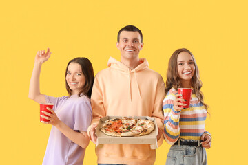 Poster - Young friends with tasty pizza and beer on yellow background