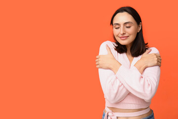 Poster - Young woman hugging herself on orange background