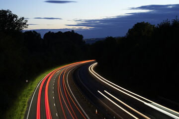 Traffic at night long exposure. Car lights in motorway. Viehicle trail lights in darkness. Front and rear lights in darkness.Highway light trail. England motorway night passing traffic. Dark backdrop