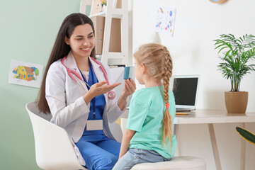 Wall Mural - Female pediatrician showing inhaler to little girl in clinic