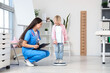 © Pixel-Shot - Female pediatrician with little girl measuring weight in clinic