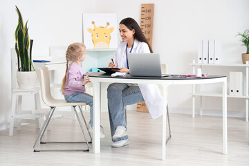 Canvas Print - Female pediatrician working with little girl at table in clinic