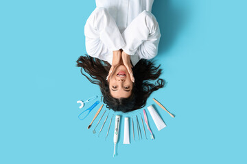 Canvas Print - Surprised young female dentist with different tools lying on blue background