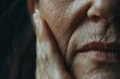 © VolumeThings - Close up of a senior woman s wrinkled face but she touches her skin after a beauty treatment emphasizing the concept of aging