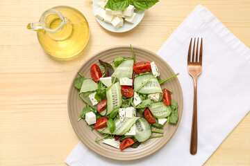 Wall Mural - Plate of fresh vegetable salad with feta cheese cubes and fork on wooden background