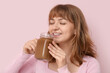 © Pixel-Shot - Happy young woman drinking tasty iced latte on pink background