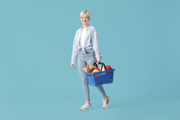 Poster - Young woman with full shopping basket on blue background