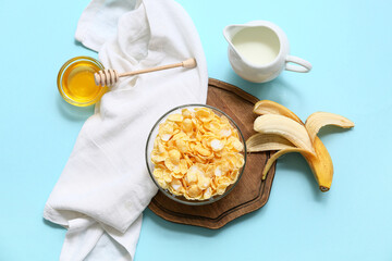 Wall Mural - Napkin, banana, bowl with cornflakes and milk on blue background