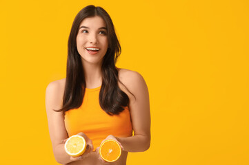 Canvas Print - Beautiful young woman with orange and lemon on color background