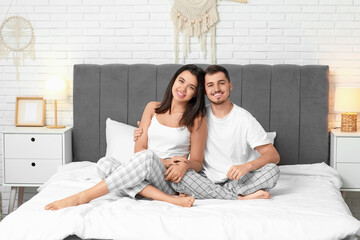 Poster - Happy young couple sitting on bed at home