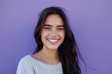 young woman smiling against a purple background