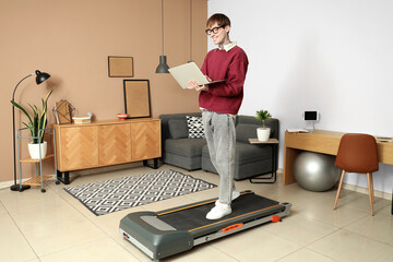 Sticker - Young businessman working with laptop on treadmill in office