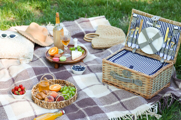 Wicker basket with tasty food and bottle of wine for romantic picnic in park