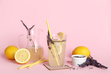 Wall Mural - Glass and jug of fresh lavender lemonade with flowers on pink background