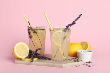 Wall Mural - Glasses of fresh lavender lemonade with flowers and lemons on pink background