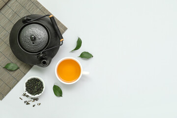 Wall Mural - Cup and teapot of hot tea with dried leaves on grey background