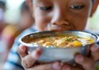 © serg3d - A young boy holds a bowl of soup, sniffing it before taking a bite. AI.