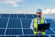 © Alan - portrait of an engineer smiling with confidence using a laptop in front of a solar panel power station, handsome male technician electrician looking at camera holding a computer