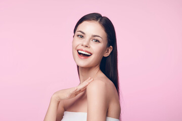 Poster - Beautiful young woman with a cheerful smile, hands on face, on a pink background