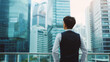 © 沈军 贡 - A businessman stands in front of tall glass buildings,