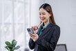 © David - Young busy happy business asian woman employee, young female corporate executive holding digital phone standing at work.