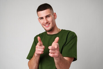 Wall Mural - Young Man in Green T-Shirt Pointing With a Smile