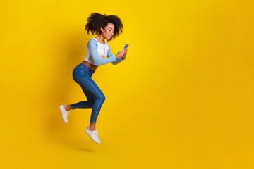 Sticker - Full body photo of attractive young woman hold device running dressed stylish blue clothes isolated on yellow color background