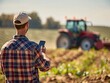 © Nikodem - Modern farmer holding phone on the field, blurred tractor in the background