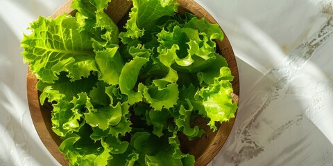 Wall Mural - wood bowl filled with fresh frillice lettuce on the white table