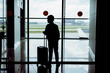 © Yulia Raneva - silhouette of caucasian boy with suitcase standing by the window in airport watching planes waiting for flight. Travelling concept