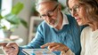 © Anna - Senior couple analyzing financial data on a digital tablet at home, focusing on retirement planning and investments. Finance, senior living, financial independence, technology adoption