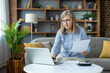 © Liubomir - Senior woman working from home on laptop. She is reviewing documents and focusing on her tasks. Concept includes remote work, home office, productivity, and senior professional.