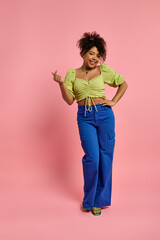 A beautiful emotional African American woman posing in stylish yellow top and blue pants against a vibrant backdrop.