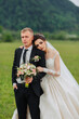 © Vasil - A bride and groom are posing for a picture in a field. The bride is wearing a white dress and the groom is wearing a suit