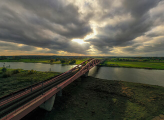 A picturesque sunset over the Hanseatic Arch in Zwolle, the Netherlands. The dramatic sky, filled with menacing clouds, creates a mesmerizing scene. 