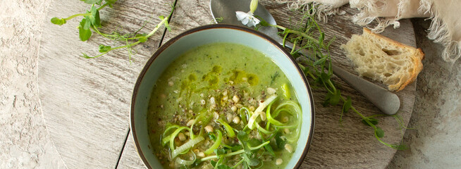 bowl with creamy soup of zucchini, spinach and broccoli on the table