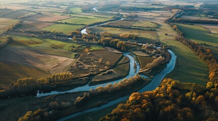 Wall Mural - Showcase an aerial view of a river winding through a rural landscape, highlighting the patchwork of fields and forests