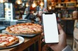 © Anna - hand holding smart phone with blank screen in pizzeria store