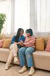© LIGHTFIELD STUDIOS - An Asian mother and her teenage daughter sitting jovially on a cozy couch in their casual wear, bonding and enjoying quality time together.
