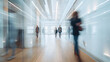 © Maksym - People in motion blur walking through an office, framed by glass walls, smooth wooden floors, and a white ceiling with strategically placed rectangular lights