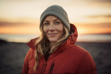 Poster - Portrait of a blissful woman in her 40s sporting a quilted insulated jacket isolated in beautiful beach sunset