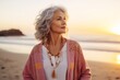 © Markus Schröder - Portrait of a tender woman in her 60s wearing a chic cardigan in beautiful beach sunset