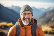 © Markus Schröder - Portrait of a happy man in his 50s sporting a trendy beanie on backdrop of mountain peaks